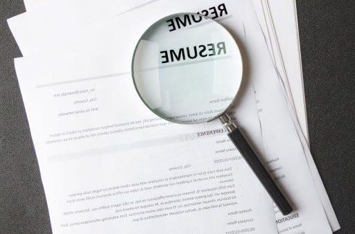 magnifying glass on top of resumes